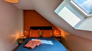 1 dormitorio con 1 cama con almohadas de color naranja y ventana en Le Clos des écureuils en Sainte-Marie-la-Blanche