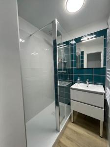Un baño con lavabo y ducha de cristal. en CAP COZ Plage, en Fouesnant