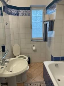 baño con lavabo y aseo y ventana en loft piccola londra, en Roma