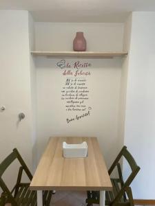 una mesa de madera con 2 sillas y un jarrón en la pared en loft piccola londra, en Roma