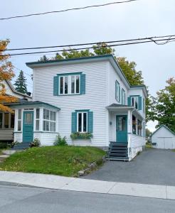 a white house with blue shutters on a street at Chez Léo par Maison Dudley in Lac-Mégantic +22 photos