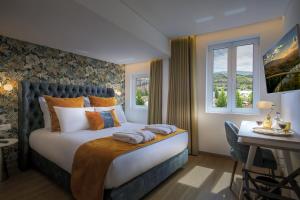 a bedroom with a bed and a desk and windows at A Tendinha - Guest House in Peso da Régua