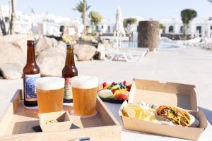 una mesa con dos botellas de cerveza y una caja de comida en MYND Yaiza, en Playa Blanca