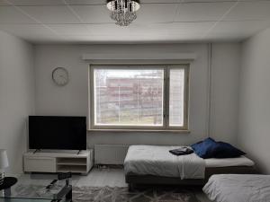 a bedroom with two beds and a tv and a window at M Apartments Piikahaka in Tampere