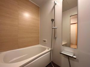 ein Badezimmer mit einer weißen Badewanne und einem Spiegel in der Unterkunft shukubo michiru 満行寺 in Hagi