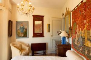 a bedroom with a bed and a chair and a chandelier at Ai Leoni Ruggenti Dimora della Storia e del Relax in Monferrato in Ottiglio +69 photos