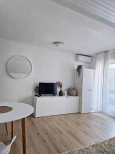 a white living room with a table and a tv at Apartments Bassanese in Bled