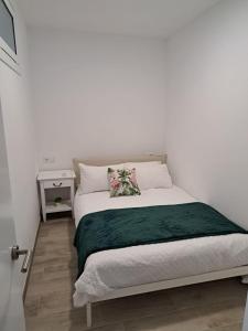 a white bedroom with a bed with a green blanket at A Casiña do Antonio in Nigrán