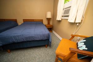 a bedroom with a bed and a chair and a window at Fair Wind Motel and Cottages in Clayton