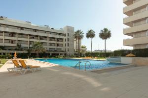 a swimming pool with two chairs and a building at Marina Vilamoura Triplex in Vilamoura