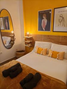 een slaapkamer met een wit bed met gele muren en een spiegel bij Retro Boutique Apt W Balcony in Historical Area in Thessaloniki