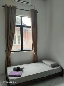 Bett in einem Zimmer mit Fenster in der Unterkunft MAA HOMESTAY BATU BURUK in Kuala Terengganu