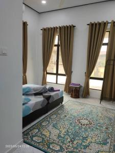 a bedroom with a bed and a rug and windows at MAA HOMESTAY BATU BURUK in Kuala Terengganu
