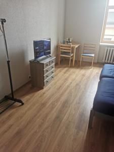 a living room with a tv and a wooden floor at Telegrafs in Ventspils