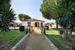 a building with a pathway leading into a yard at Casa Montepinar in Chiclana de la Frontera