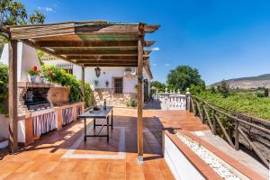 una terraza de madera con mesa y pérgola en Ladera de los molinos, en El Padul