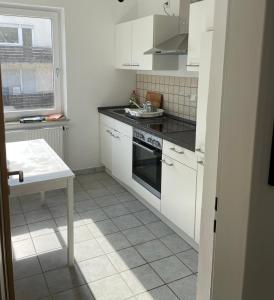uma cozinha com armários brancos e um forno com placa de fogão em Ferienwohnung FM Moselle em Reil