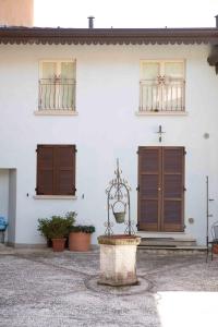 ein weißes Gebäude mit braunen Türen und einem Brunnen in der Unterkunft Borgo alla Sorgente in Vallio Terme