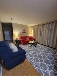 uma sala de estar com uma cadeira azul e um sofá vermelho em Cozy apt in center of Saint John NB em Saint John