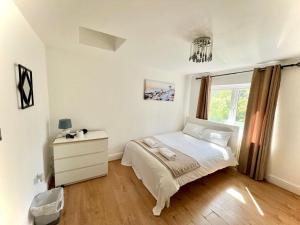 ein Schlafzimmer mit einem Bett, einer Kommode und einem Fenster in der Unterkunft Canary Wharf Holiday Rooms in London