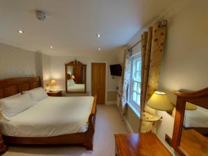 a bedroom with a large bed and a mirror at Rose in Vale Country House Hotel in St. Agnes 