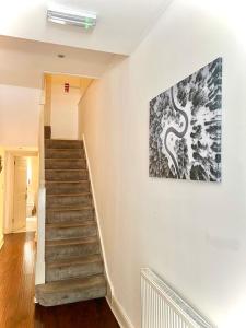 una escalera en una casa con una pintura en la pared en Canary Wharf Holiday Rooms, en Londres