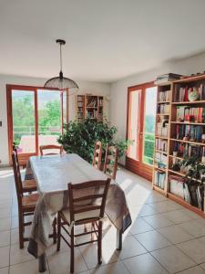 a dining room with a table and chairs and bookshelves at Maison au calme in Viry
