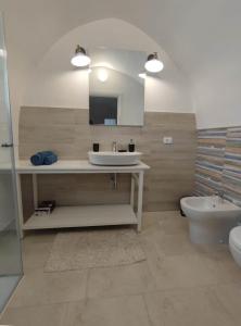 La salle de bains est pourvue d'un lavabo, de toilettes et d'un miroir. dans l'établissement La Mia Corte, à Tuglie