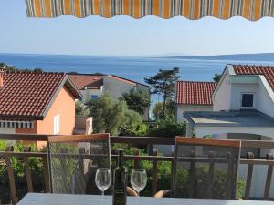 a table with two wine glasses on a balcony at Vila Beleca Krk - Apartments Rest & Sea in Krk