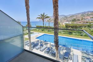 a balcony with a view of a pool and palm trees at Golden Residence Hotel in Funchal