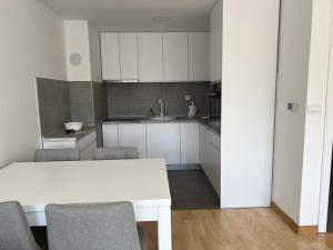 - une cuisine avec des placards blancs, une table et des chaises dans l'établissement Apartment River, à Bratunac