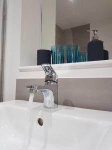 a bathroom sink with a faucet and glasses on a shelf at Contractor Bookers At Infinity Apartments in Liverpool