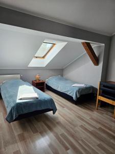 a attic bedroom with two beds and a skylight at Hotel Helikon in Yanoshi