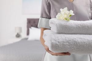 a woman holding a stack of towels in a hotel room at PARK SIGNATURE HOTELS - Royal Benza in Vijayawāda