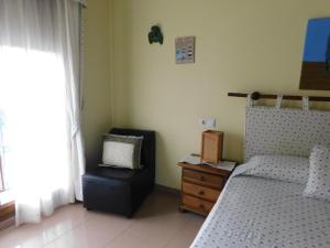 a bedroom with a bed and a chair next to a window at Apartamentos As Caldelas in O Grove +98 photos