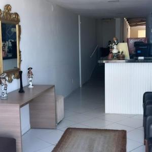 a living room with a table and a mirror at Jampa Mar Pousada in João Pessoa