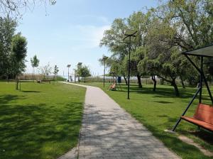 un camino en un parque con un banco y árboles en Nosztalgia Apartman Balatonkenese, en Balatonkenese