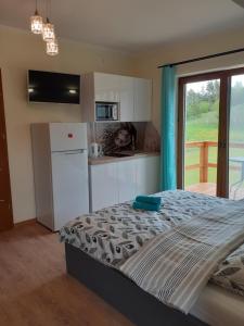 a bedroom with a bed and a kitchen with a window at Apartamenty Nad Jeziorem in Postawele +77 photos