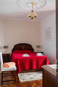 a bedroom with a red bed and a chandelier at Sunset House in Câmara de Lobos