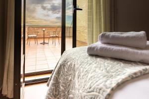 1 dormitorio con cama y vistas a un balcón en CASA RURAL Cigarral del Pintor, en Toledo