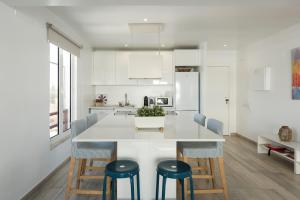 a kitchen with a large white island with blue stools at Marina Vilamoura Relax Apartment in Vilamoura