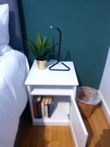 a white nightstand with a plant and a lamp on it at Platinum Apartment Birmingham- Free Secure Parking- Fast Fibre Wi-Fi in Birmingham