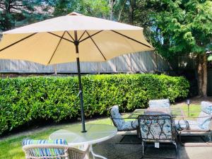 Lucy’s Elegant & Cozy House في Sammamish: طاولة وكراسي مع مظلة على الفناء