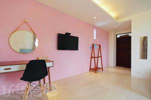 a room with a pink wall with a mirror and a chair at Encounter Dream House in Green Island