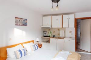 a bedroom with a bed and a kitchen with white cabinets at Alexandra's House in Skiathos