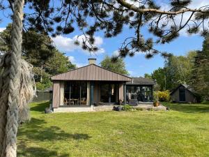 a small house in a yard with a tree at Lovely Holiday Home Close To The Beach And Nature in Rødby +32 photos