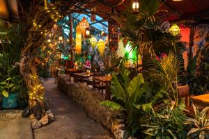 a restaurant with plants and tables and lights at Los Amigos Hostel in Flores