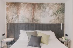 a bedroom with a white bed with a tropical wallpaper at VillaLume in Marina di Castagneto Carducci