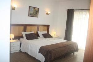 a bedroom with a large bed with white sheets and pillows at Rustic Villa Guesthouse in Santa Bárbara de Nexe