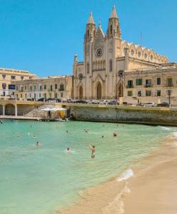 a group of people in the water in front of a building at Ewa Apt - 3-Bedrooms Apt near Sliema - St Julians Seafront in Il-Gżira
